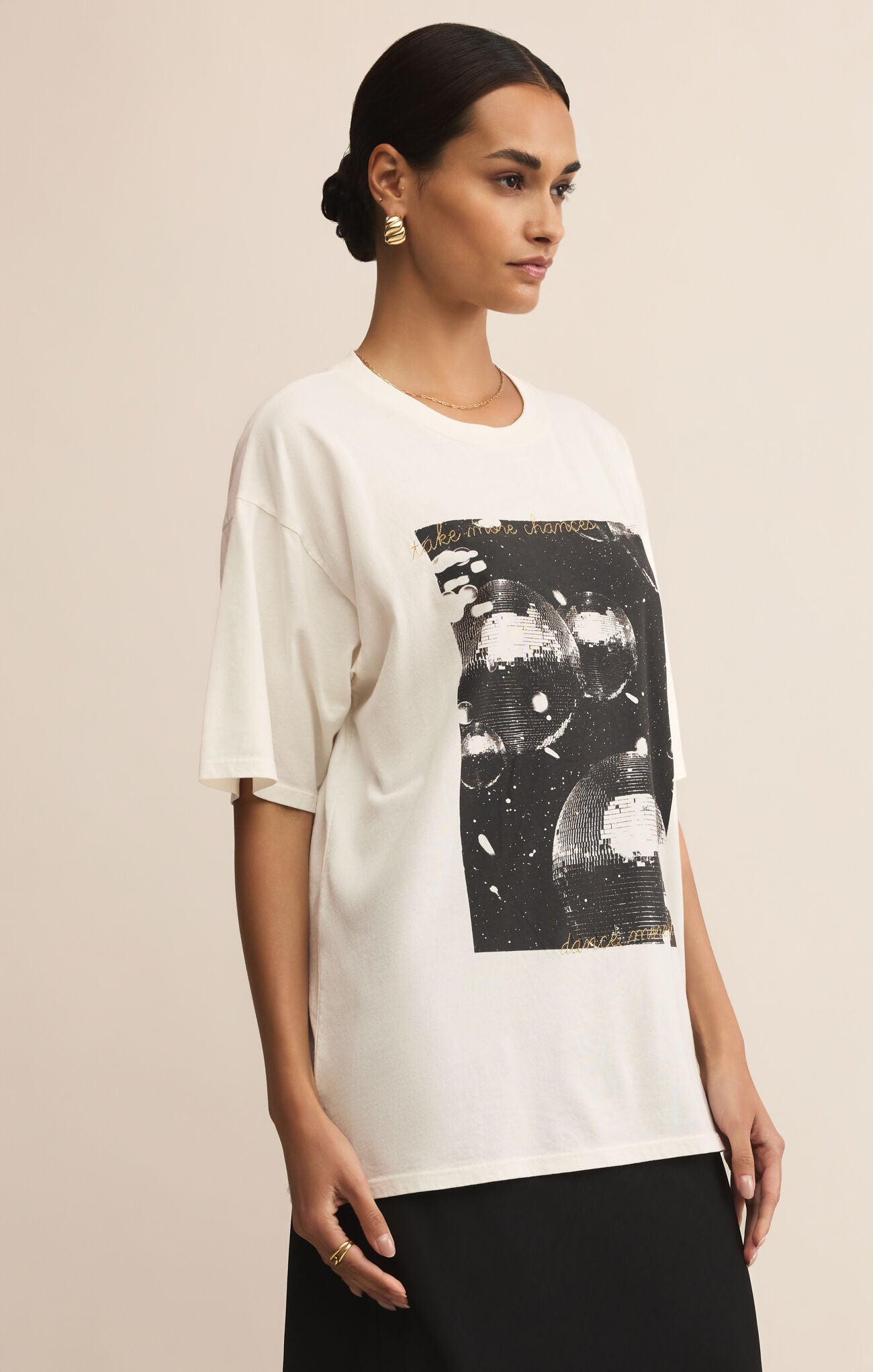 Woman wearing a white t-shirt with black graphic design on a beige background