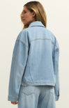 Person wearing a light blue denim jacket on a plain background