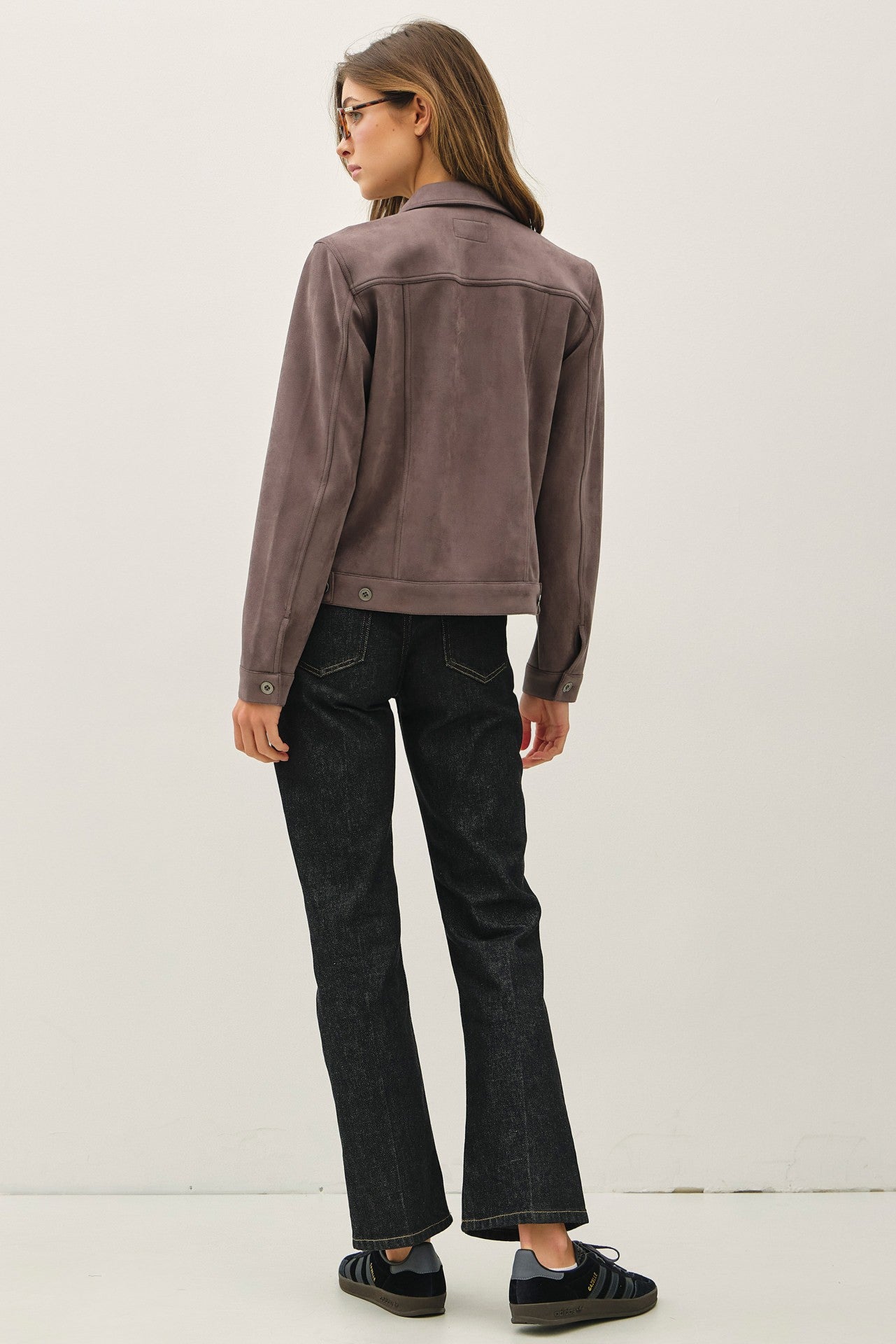 Person wearing a brown jacket and black pants on a white background