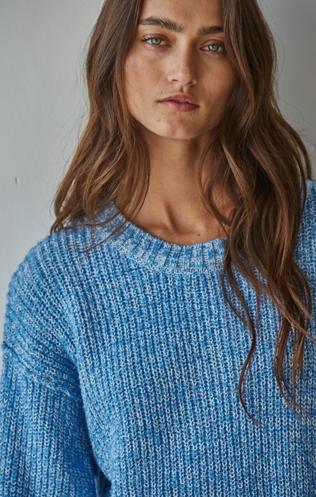 Woman wearing a blue knitted sweater against a neutral background