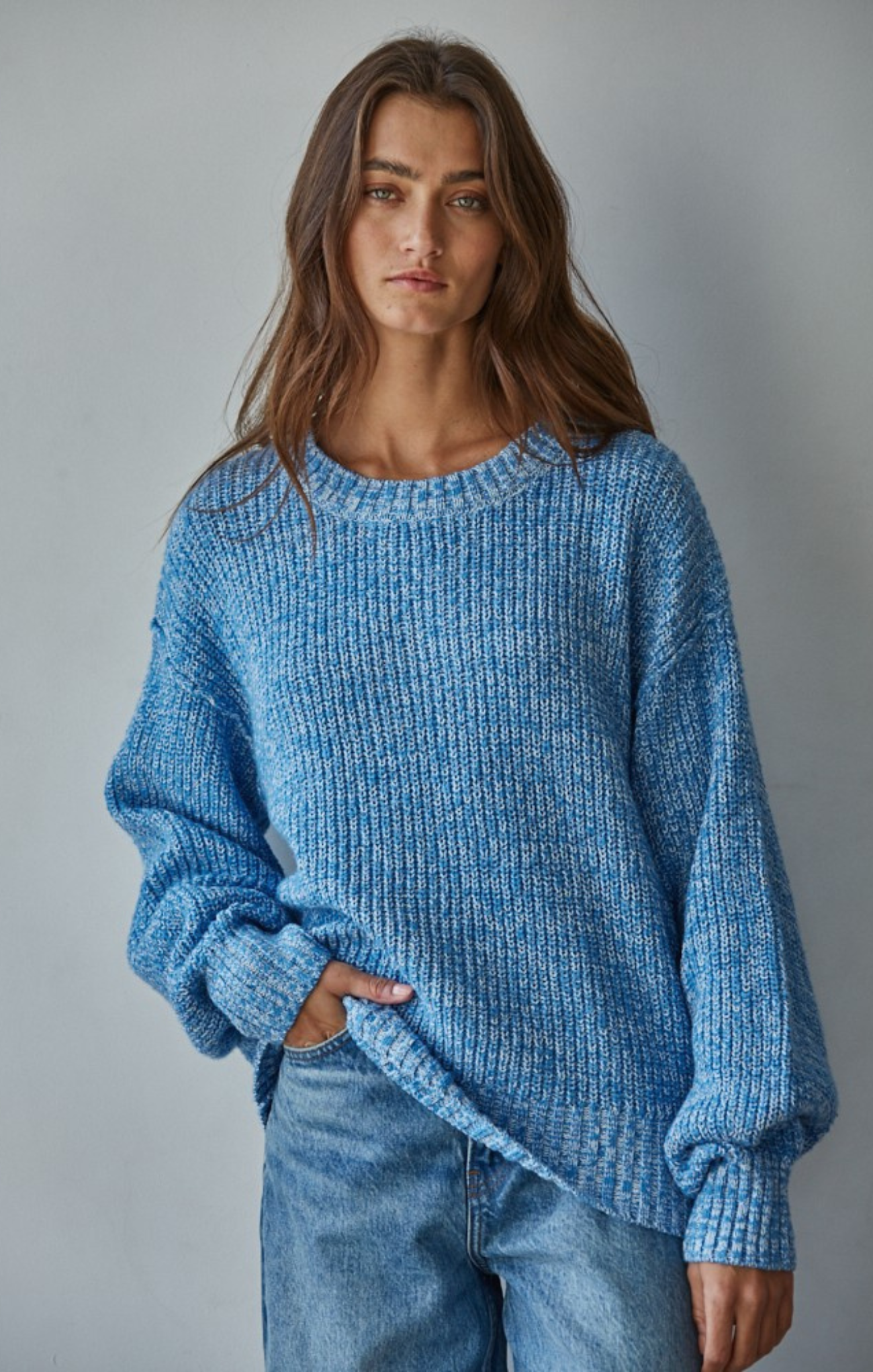 Woman wearing a blue knitted sweater against a gray background