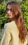 Woman wearing a yellow knitted sweater against a neutral background
