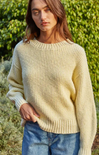 Woman wearing a yellow knitted sweater against a neutral background