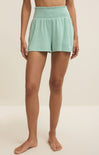 Person wearing light green shorts on a beige background