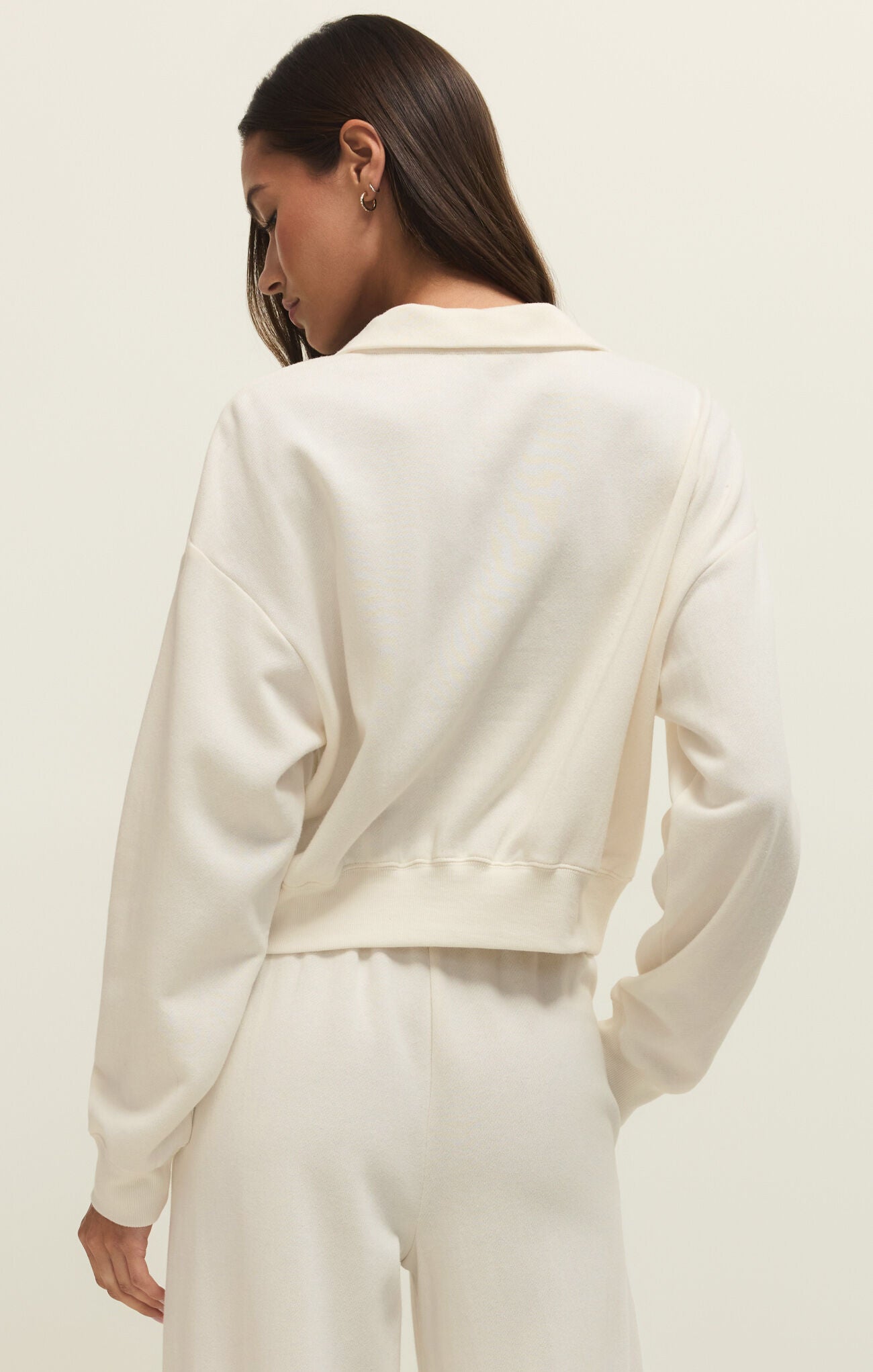 Person wearing a cream-colored blazer and pants on a plain background