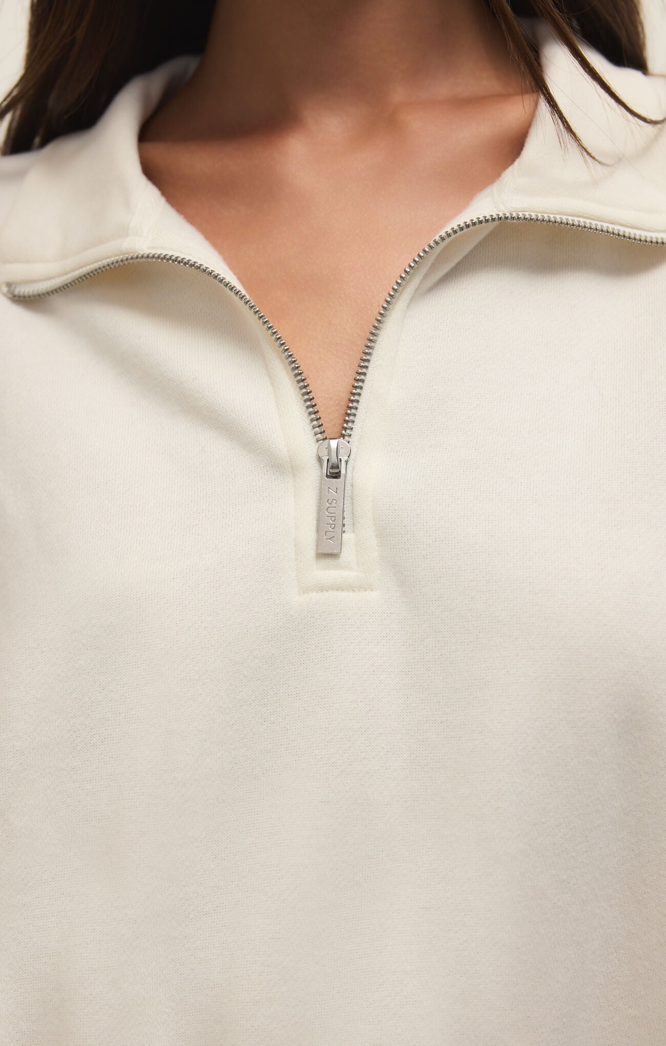 Close-up of a white zip-up sweatshirt with a zipper detail.