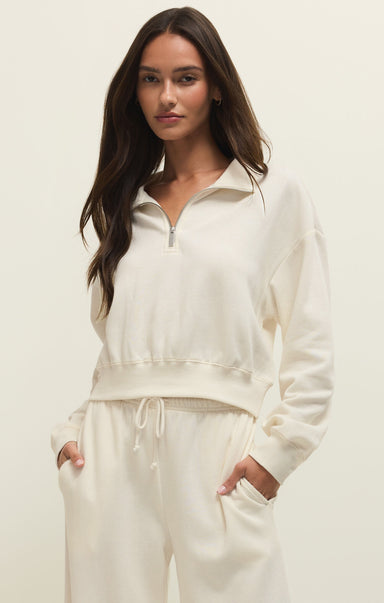 Woman wearing a white zip-up sweatshirt and pants on a plain background