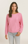 Woman wearing a pink sweater and light gray pants on a beige background