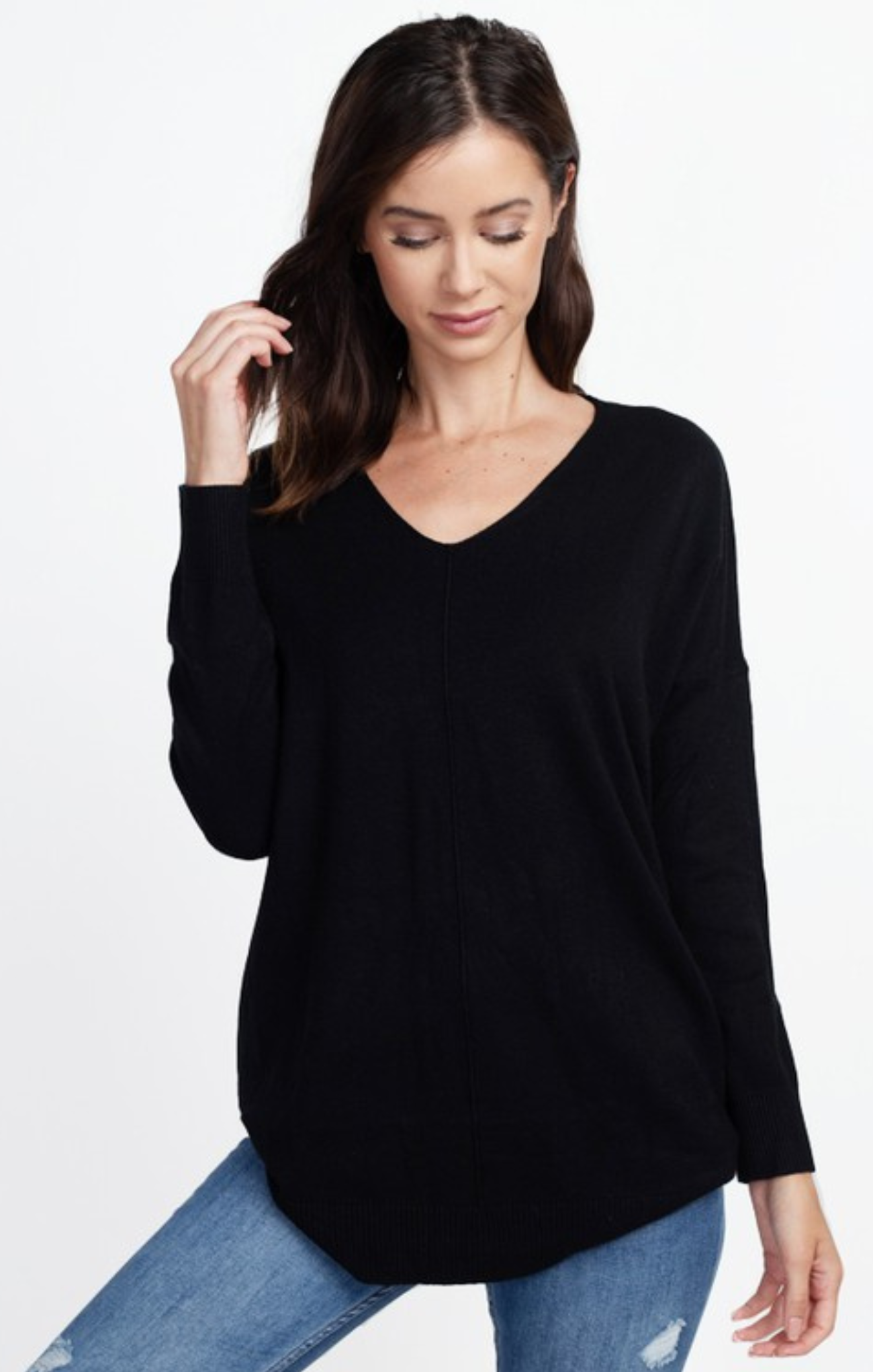 Woman wearing a black sweater and blue jeans on a white background