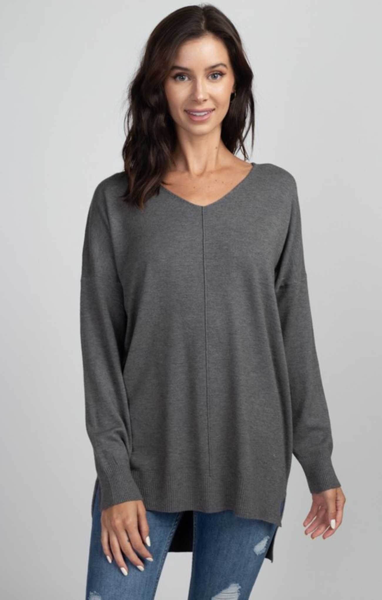 Woman wearing a gray long-sleeve top against a plain background