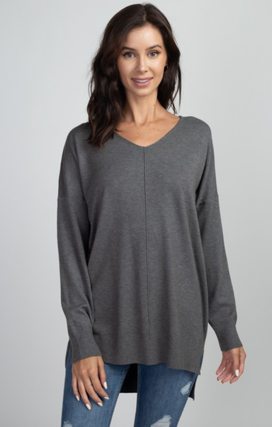 Woman wearing a gray long-sleeve top against a plain background