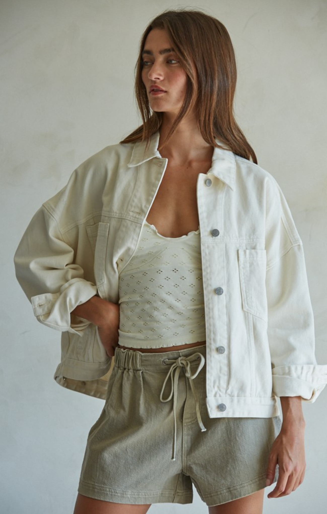 Woman wearing a white jacket and green shorts against a plain background