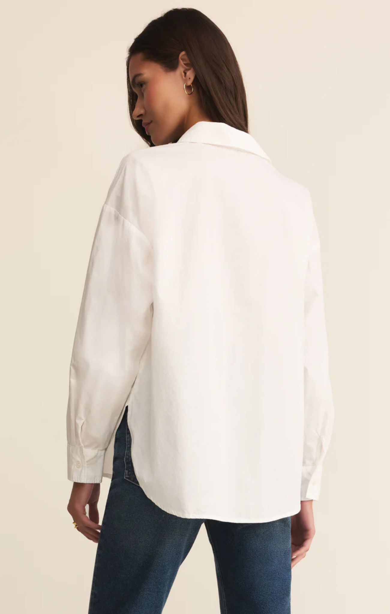 Woman wearing a white shirt and blue jeans on a beige background