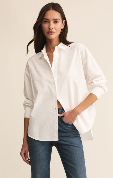 Woman wearing a white shirt and blue jeans on a beige background