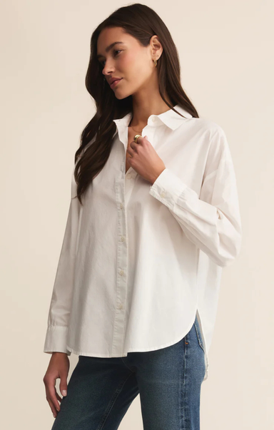 Woman wearing a white shirt and blue jeans against a beige background