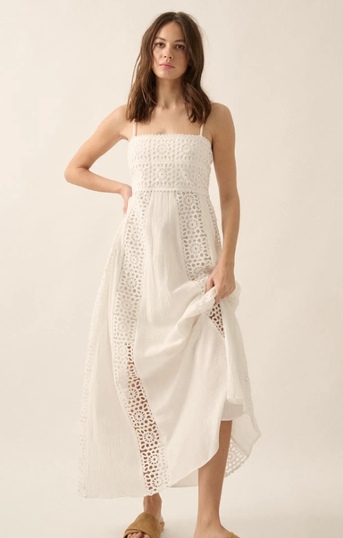 Woman wearing a white strapless dress with lace details on a plain background