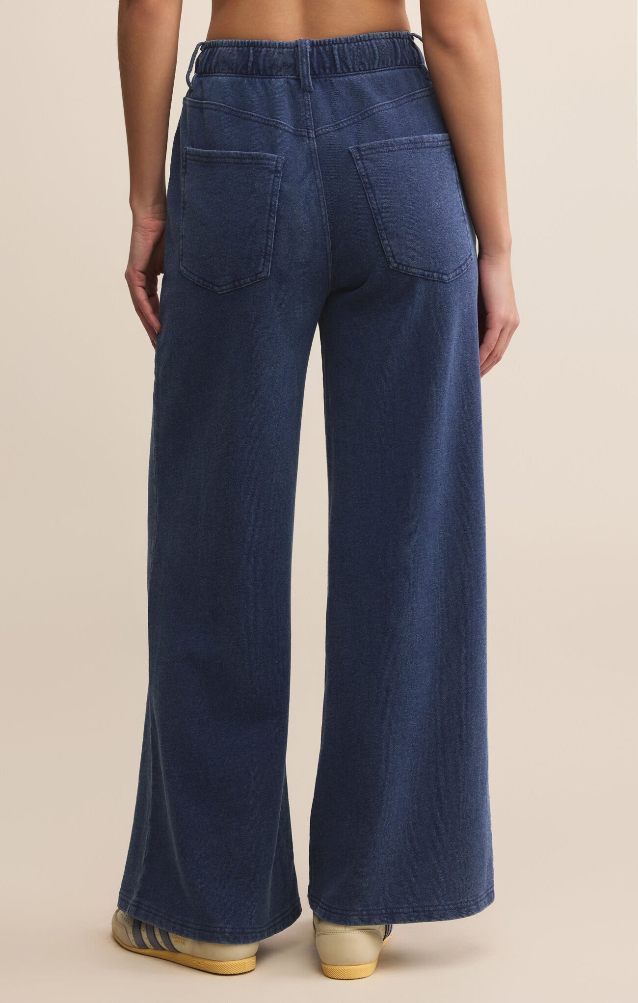 Navy blue wide-leg jeans worn by a person on a beige background