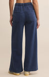 Navy blue wide-leg jeans worn by a person on a beige background