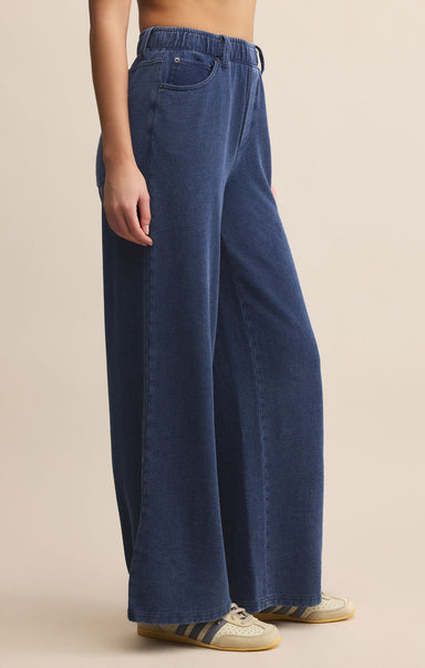 Person wearing blue wide-leg jeans on a beige background