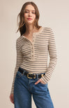 Woman wearing a striped long-sleeve top and blue jeans on a beige background