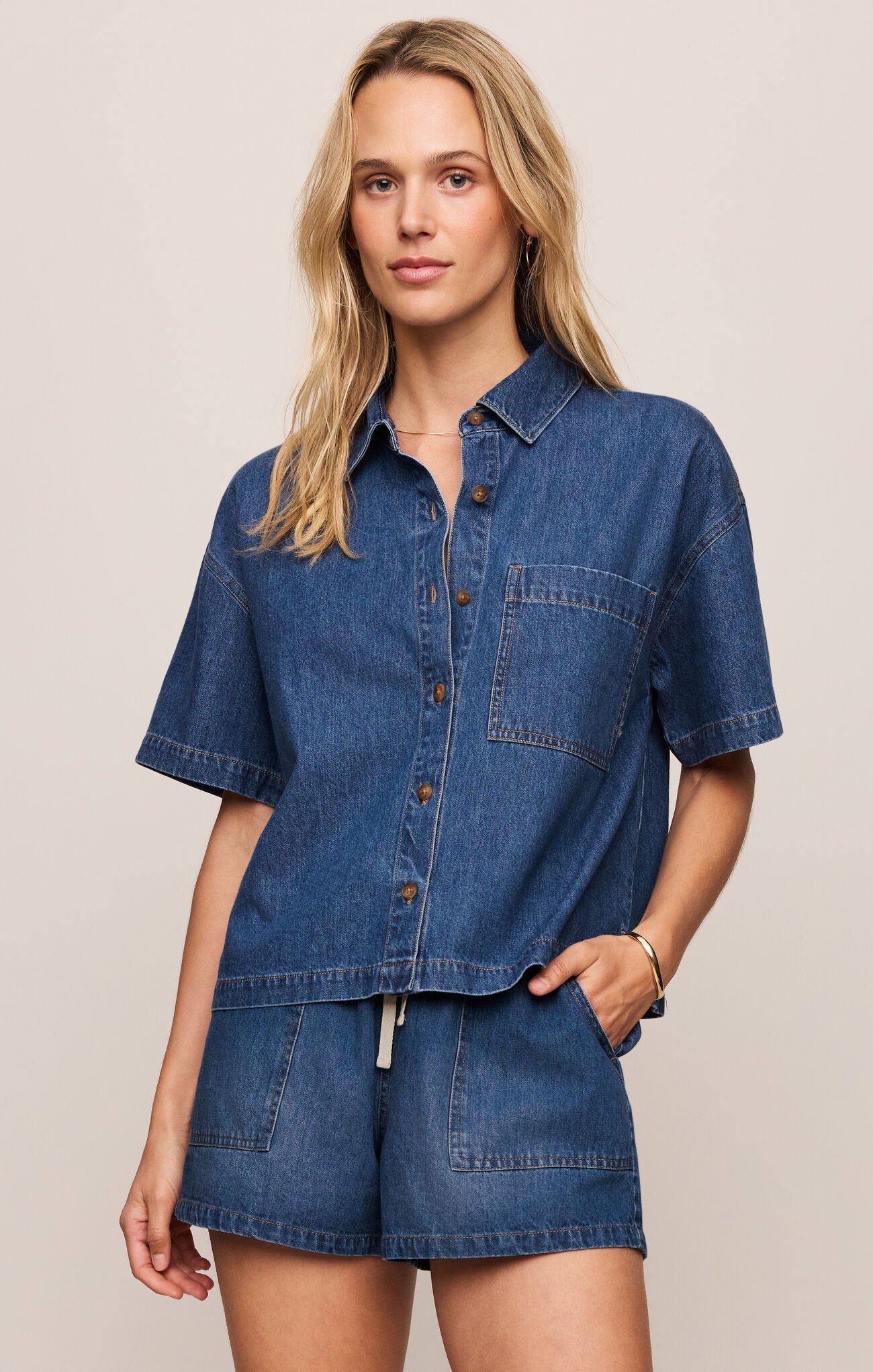 Woman wearing a blue denim outfit on a beige background