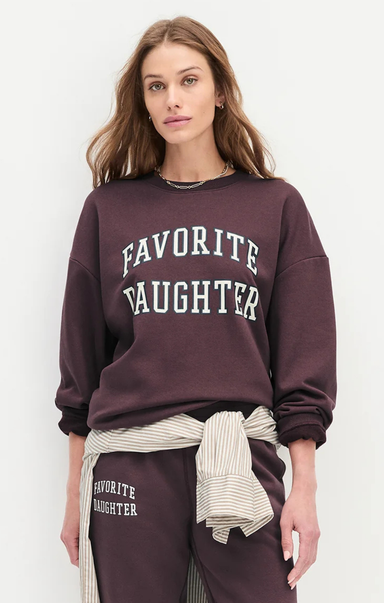 Woman wearing a maroon 'Favorite Daughter' sweatshirt and pants on a white background