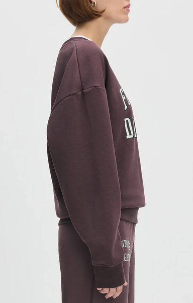 Person wearing a maroon sweatshirt with text on the sleeve against a white background