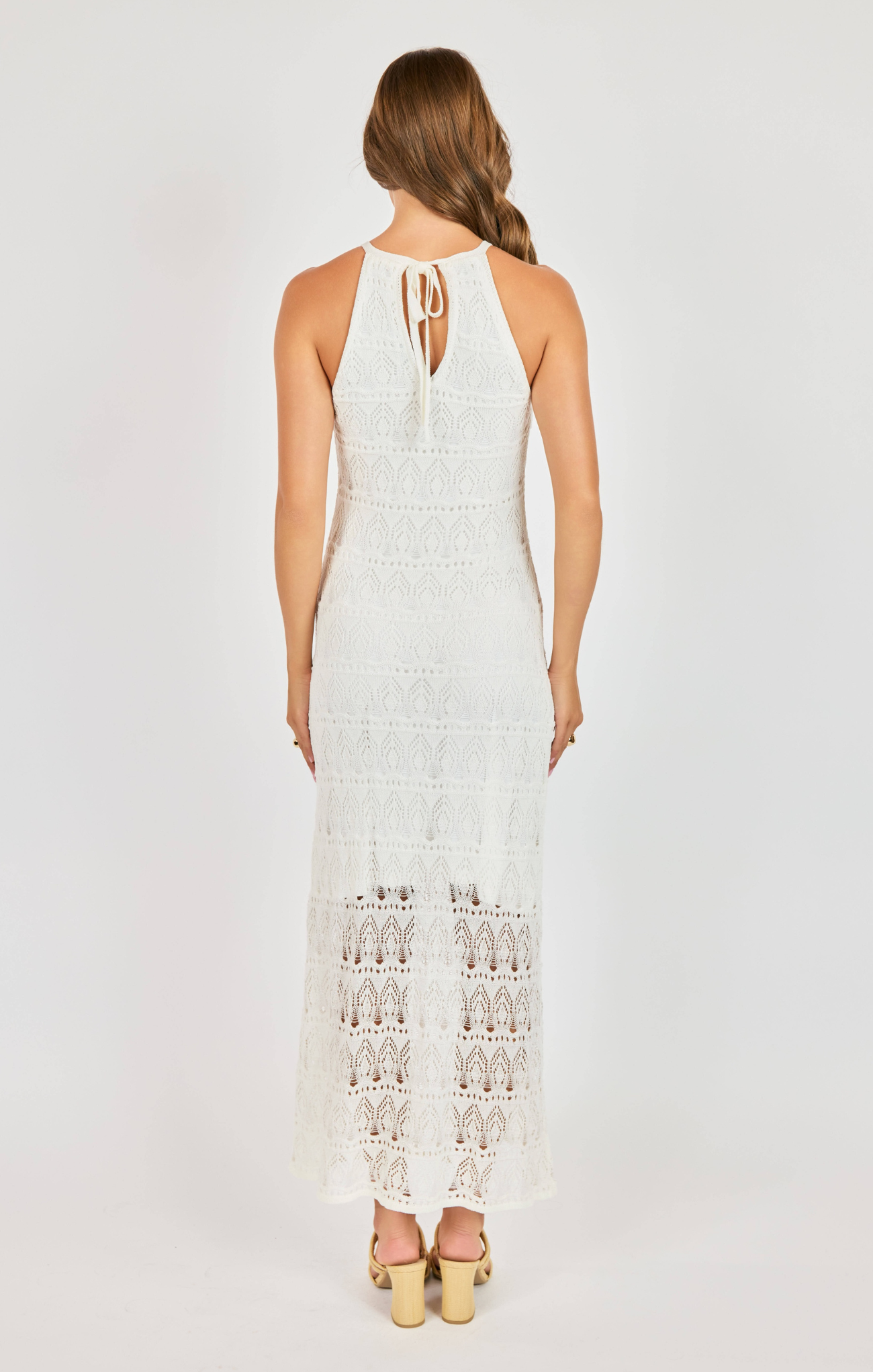 Woman wearing a white lace dress on a plain background