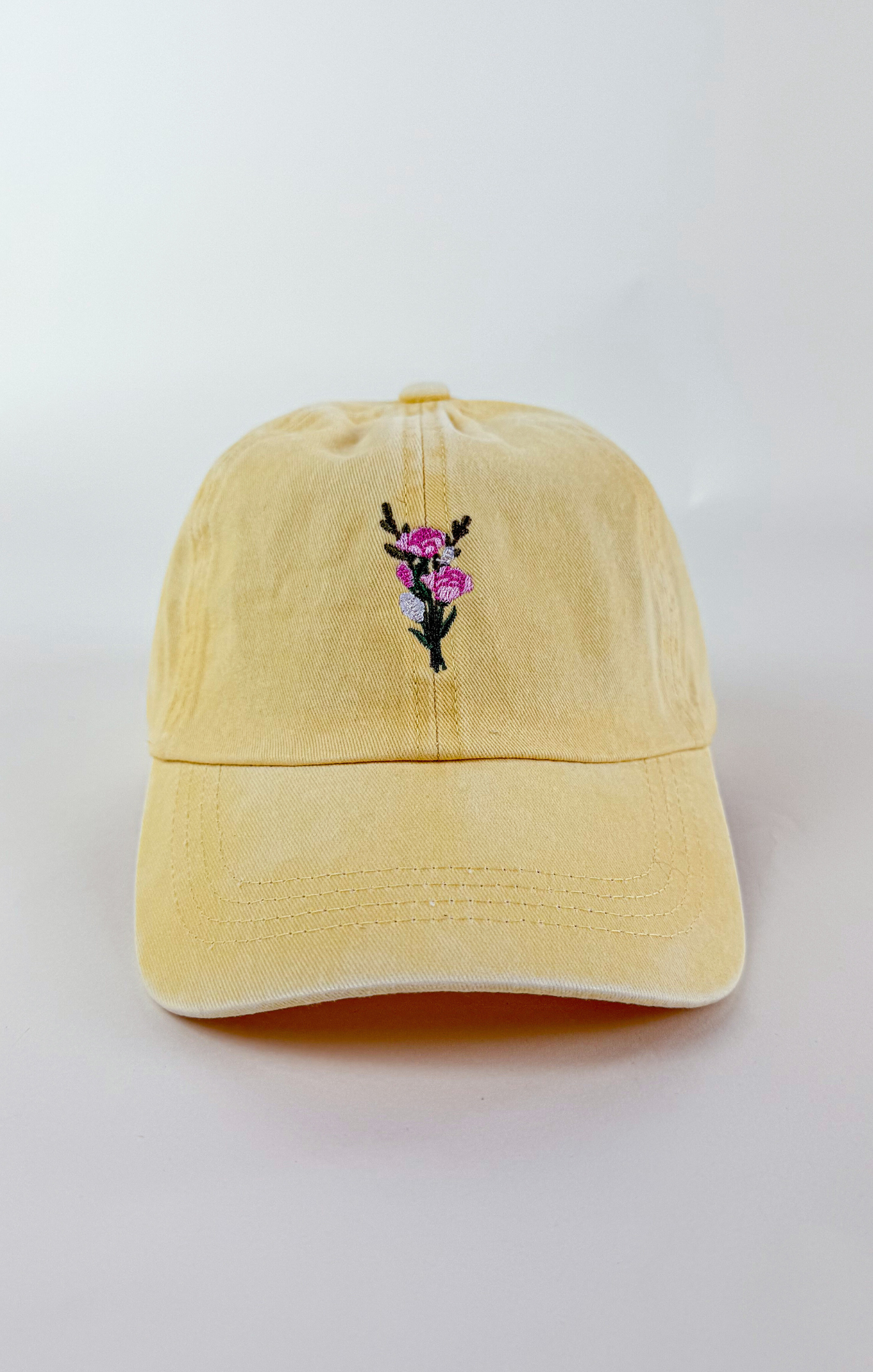 Butter yellow baseball cap with a small embroidered pink and purple flower bouquet centered on the front.