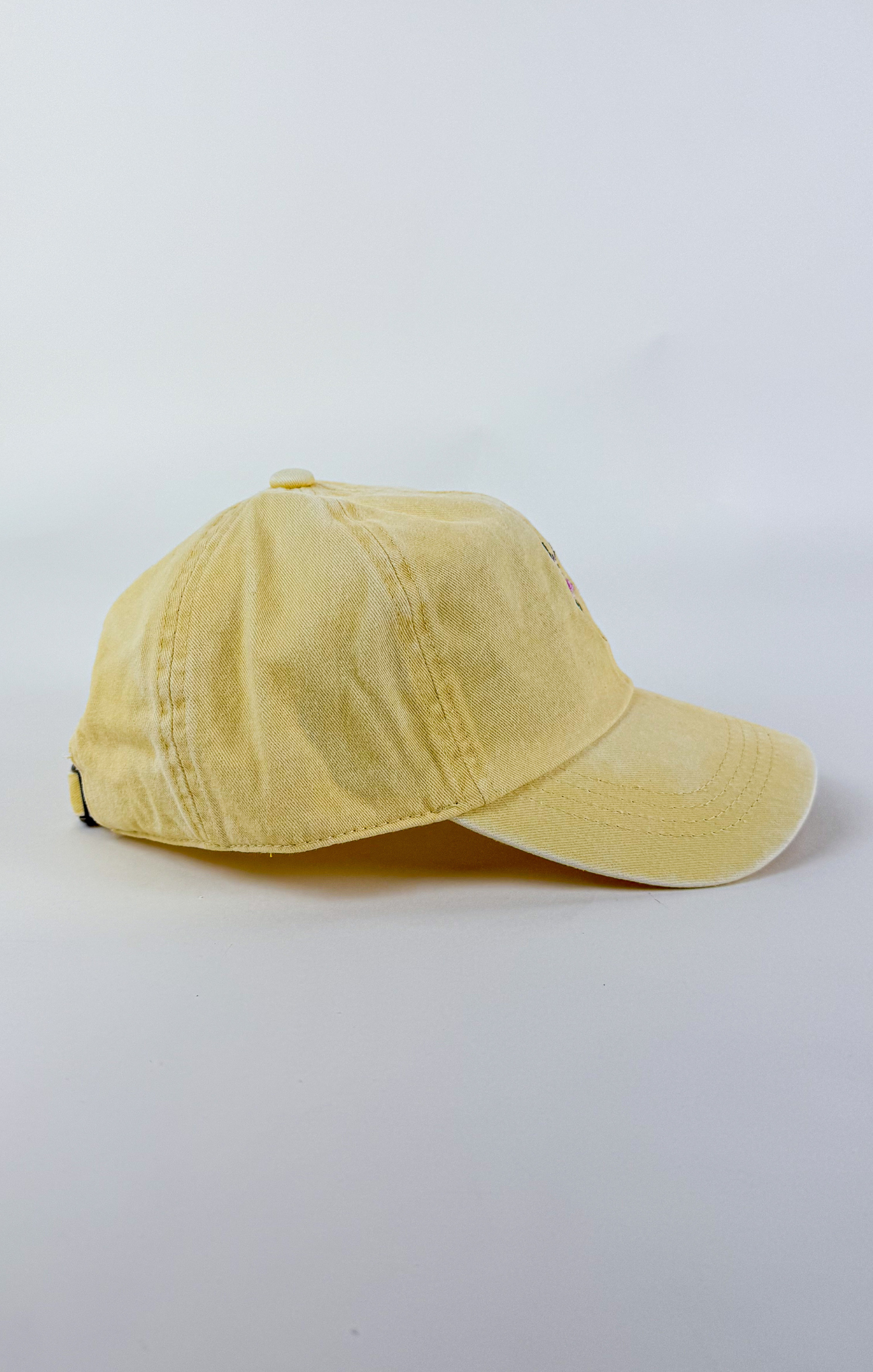 Butter yellow baseball cap with a small embroidered pink and purple flower bouquet centered on the front.