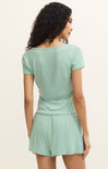 Woman wearing a light green romper against a plain background