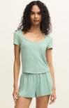 Woman wearing a light green top and shorts set on a beige background