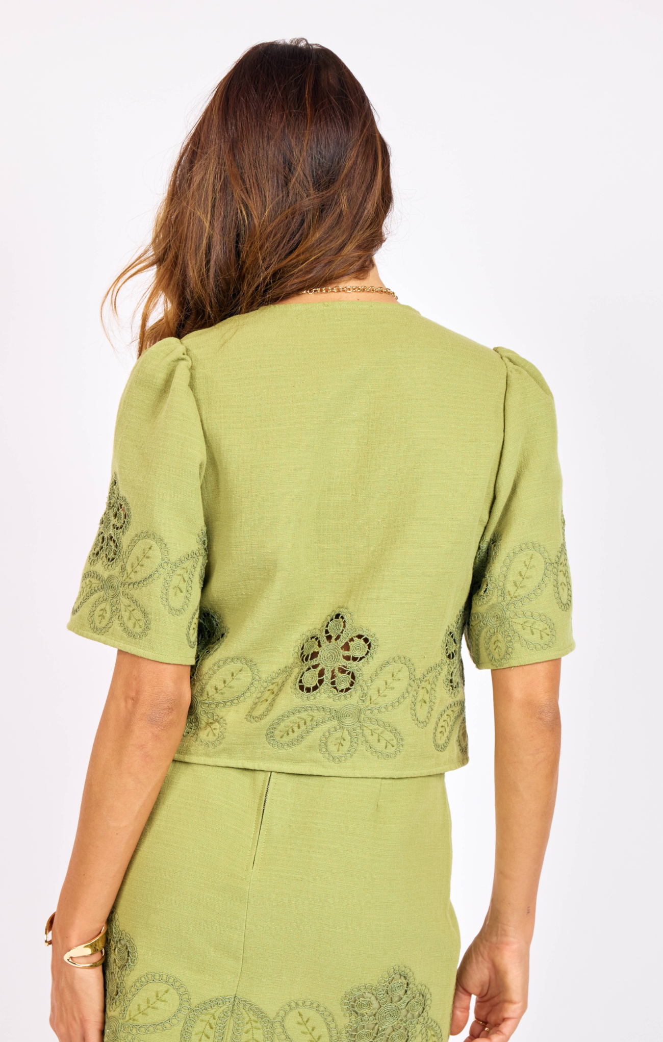 Green embroidered top worn by a person on a white background