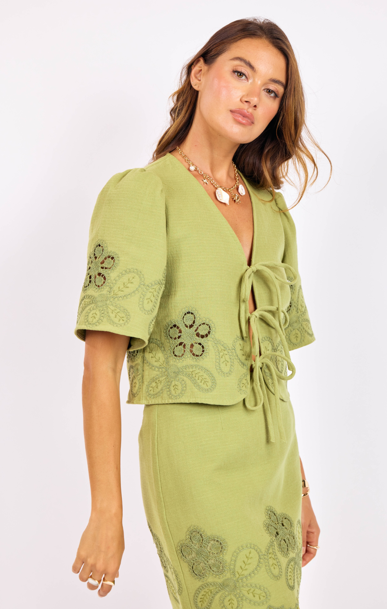 Woman wearing a green dress with embroidery on a white background