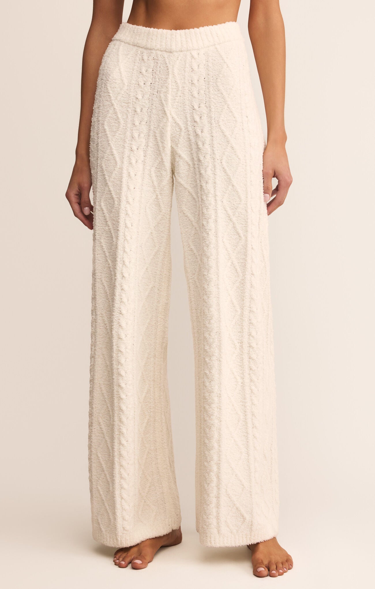 Person wearing white cable knit pants on a plain background