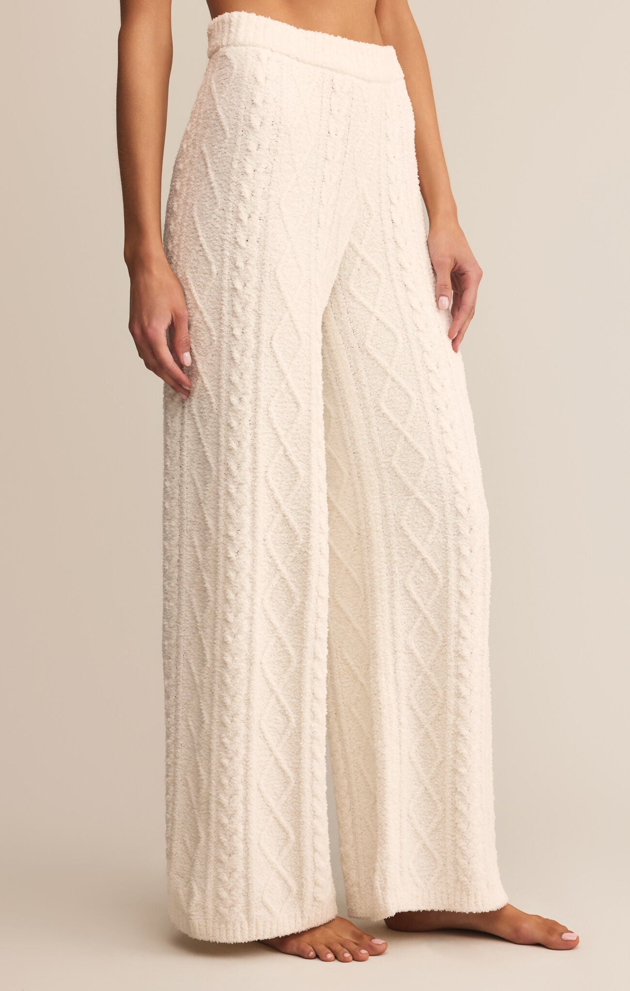 White textured pants worn by a person on a beige background