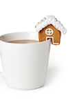 Gingerbread house with marshmallows on top of a white mug filled with hot chocolate.