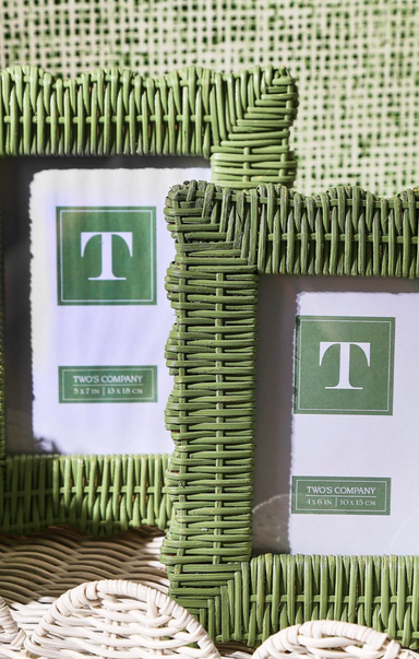 Two green wicker picture frames with a brand label on a textured surface.