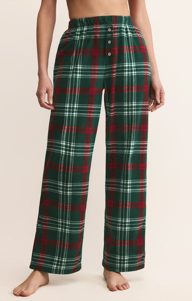 Green plaid pajama pants worn by a person on a beige background