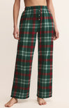 Green plaid pajama pants worn by a person on a beige background