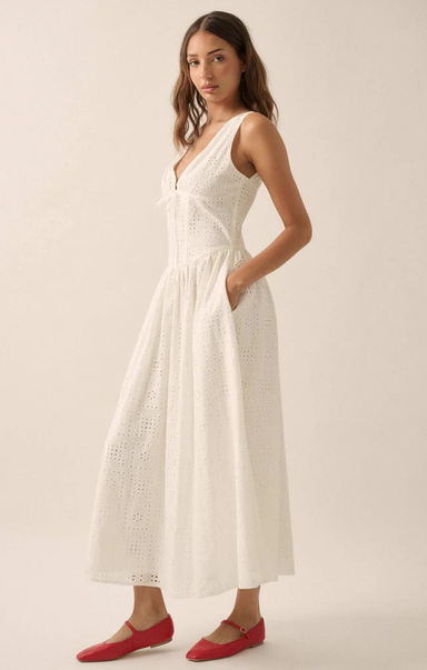 Woman wearing a white dress with red shoes on a plain background