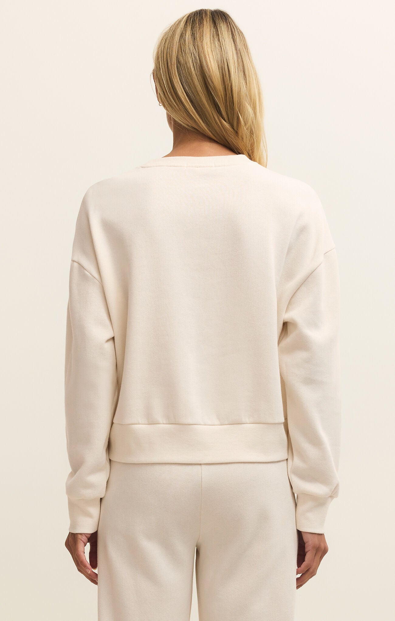 Person wearing a beige outfit with a plain background