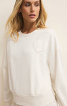 Woman wearing a white sweatshirt with a heart design on a plain background