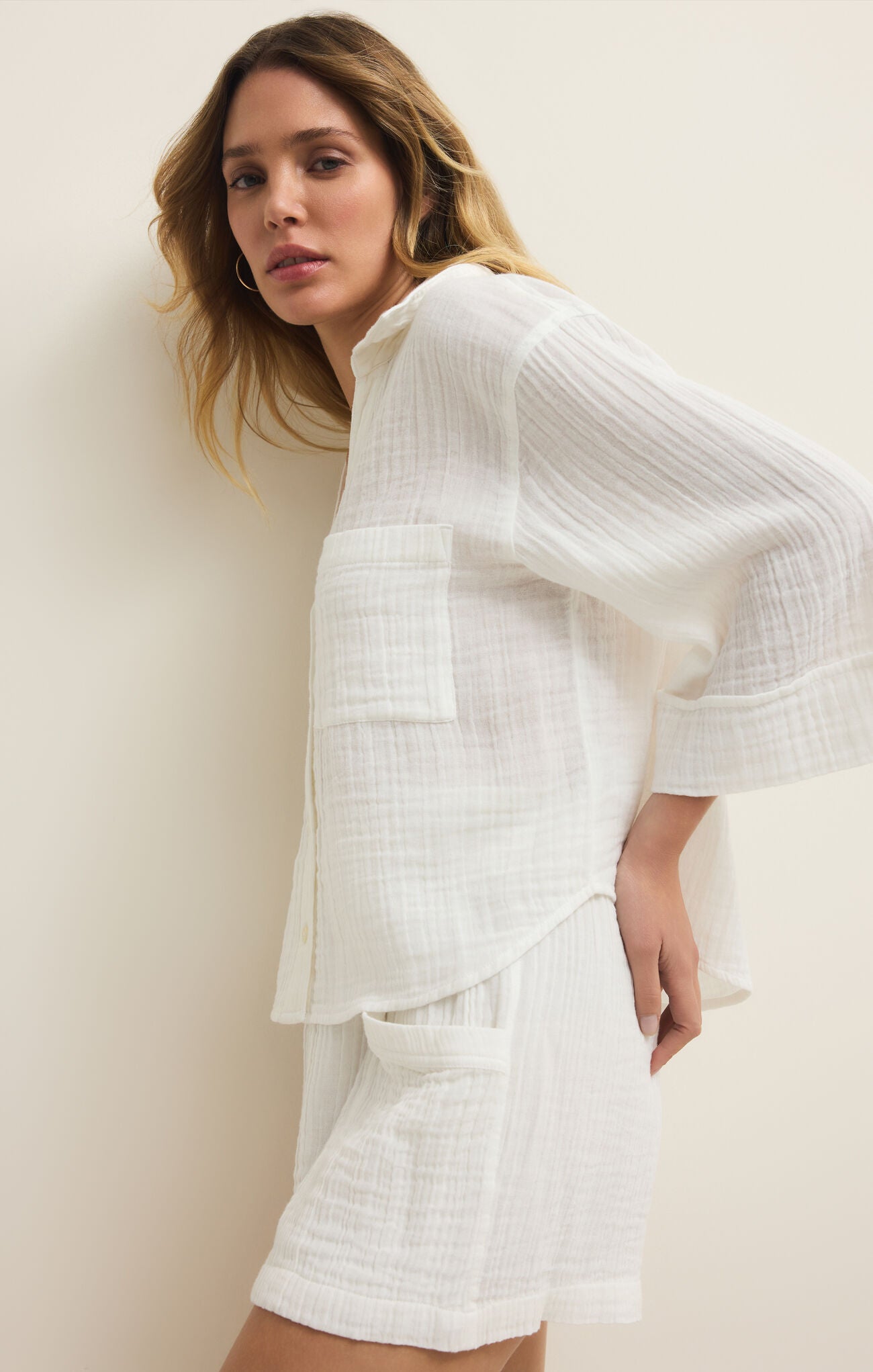 Woman wearing a white outfit against a plain background