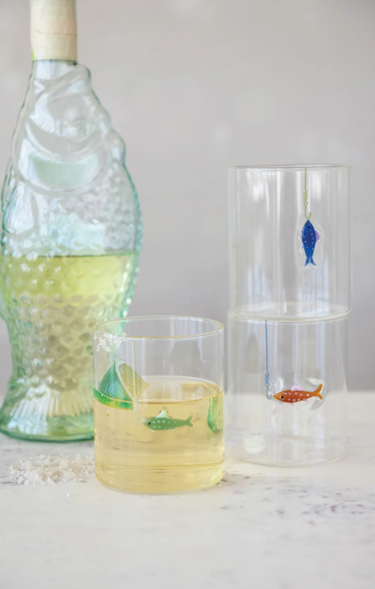 Decorative glass bottles with fish designs on a white surface