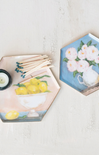 Hexagonal coasters with floral and lemon designs on a light surface