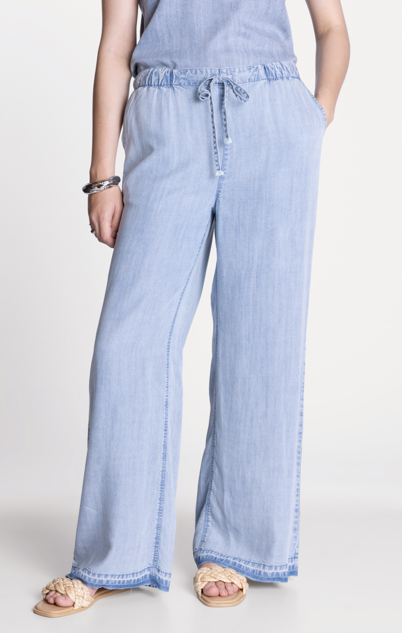 Light blue denim wide-leg pants worn by a person on a white background