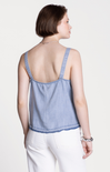 Woman wearing a blue denim top with thin straps on a white background