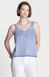 Woman wearing a blue striped tank top and white pants on a light background