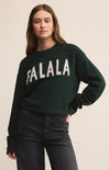 Person wearing a dark green sweater with 'FA LA LA' text on a beige background
